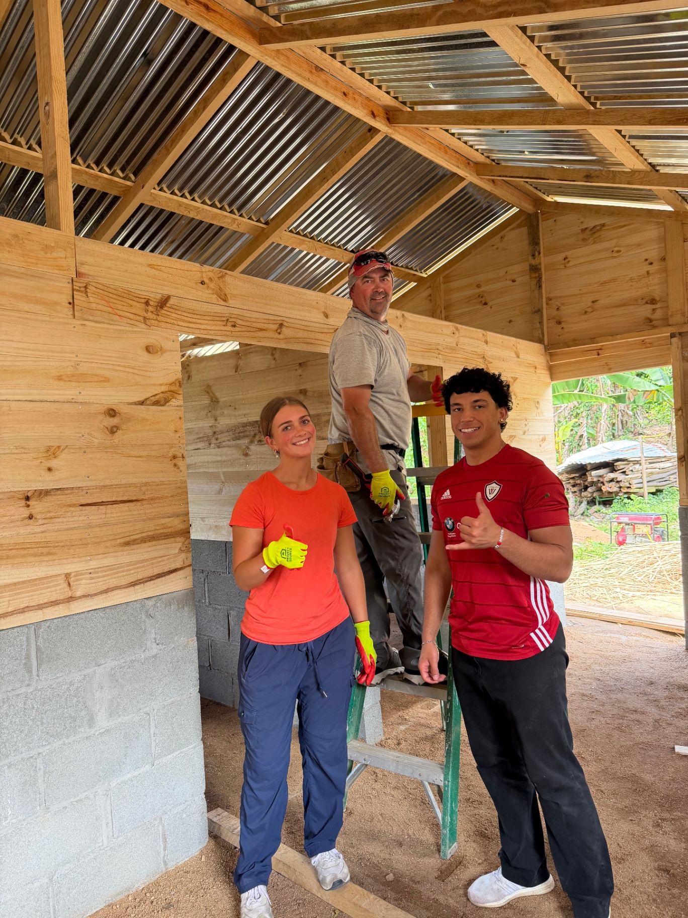 Volunteers giving a thumbs up while framing a home's roof