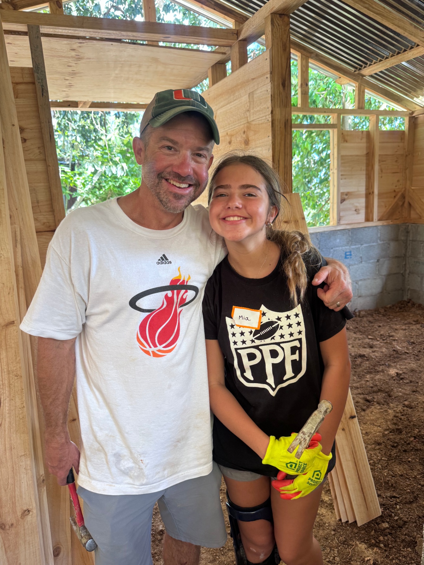 Volunteer and young helper smiling inside a home under construction