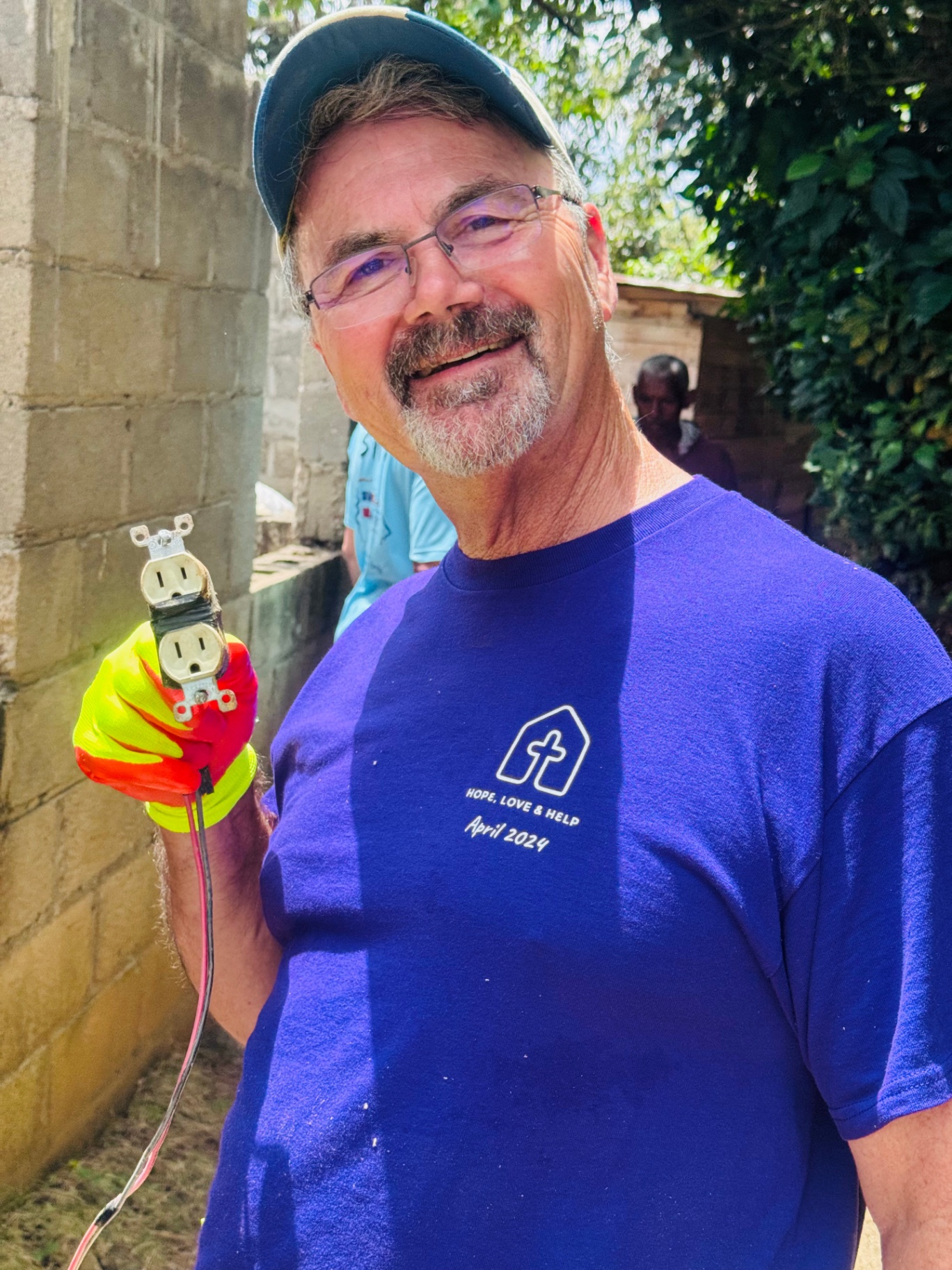 Volunteer holding up a newly wired electrical outlet