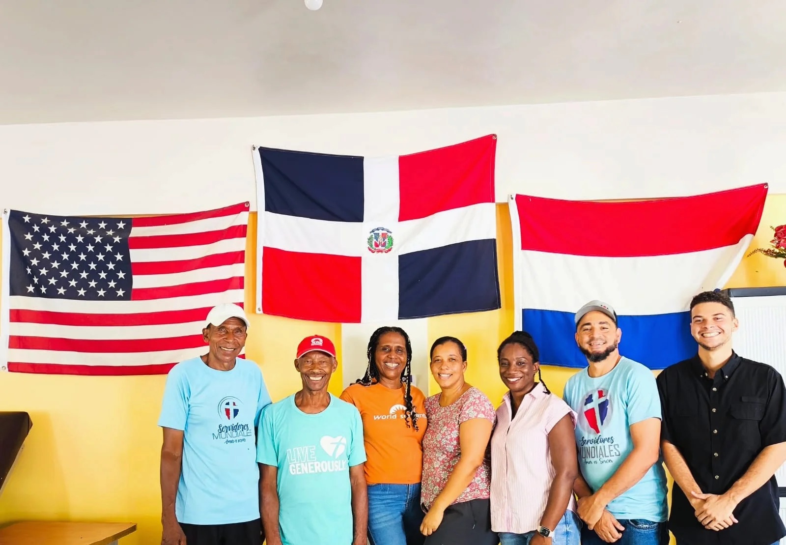 Team posing together in front of American and Dominican flags