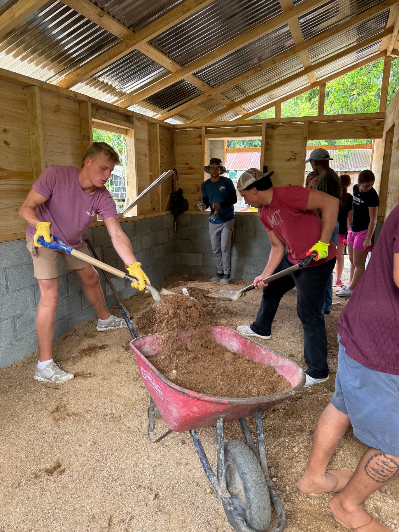 Volunteers shoveling and moving gravel inside a home