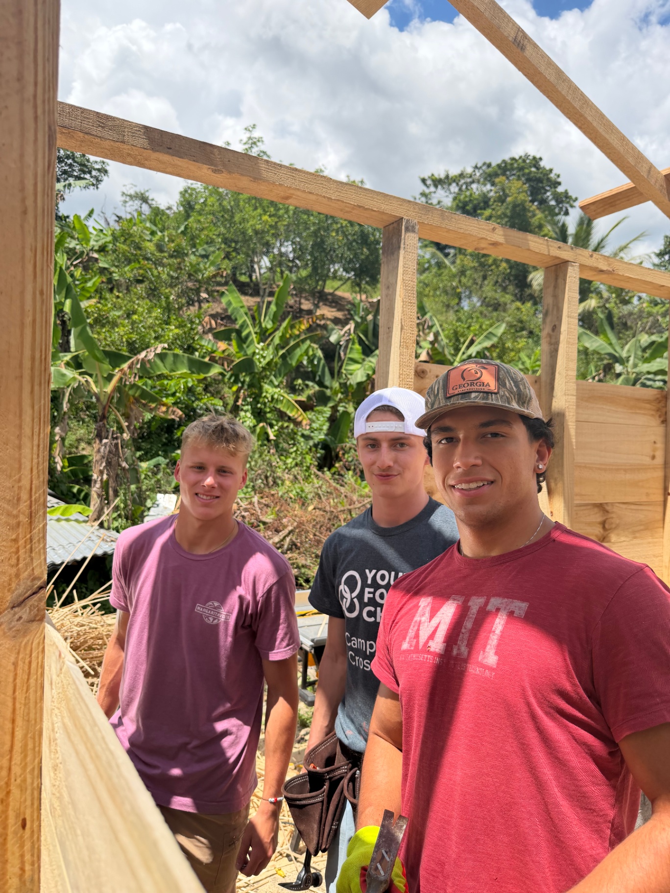 Three young volunteers standing inside a home under construction
