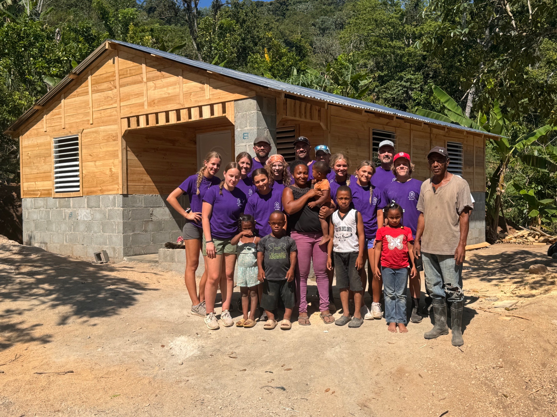 Volunteer team and family in front of a newly built home