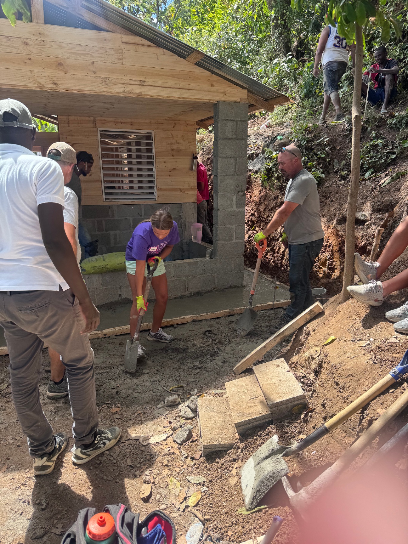 Volunteers and local workers pouring fresh concrete outside a home