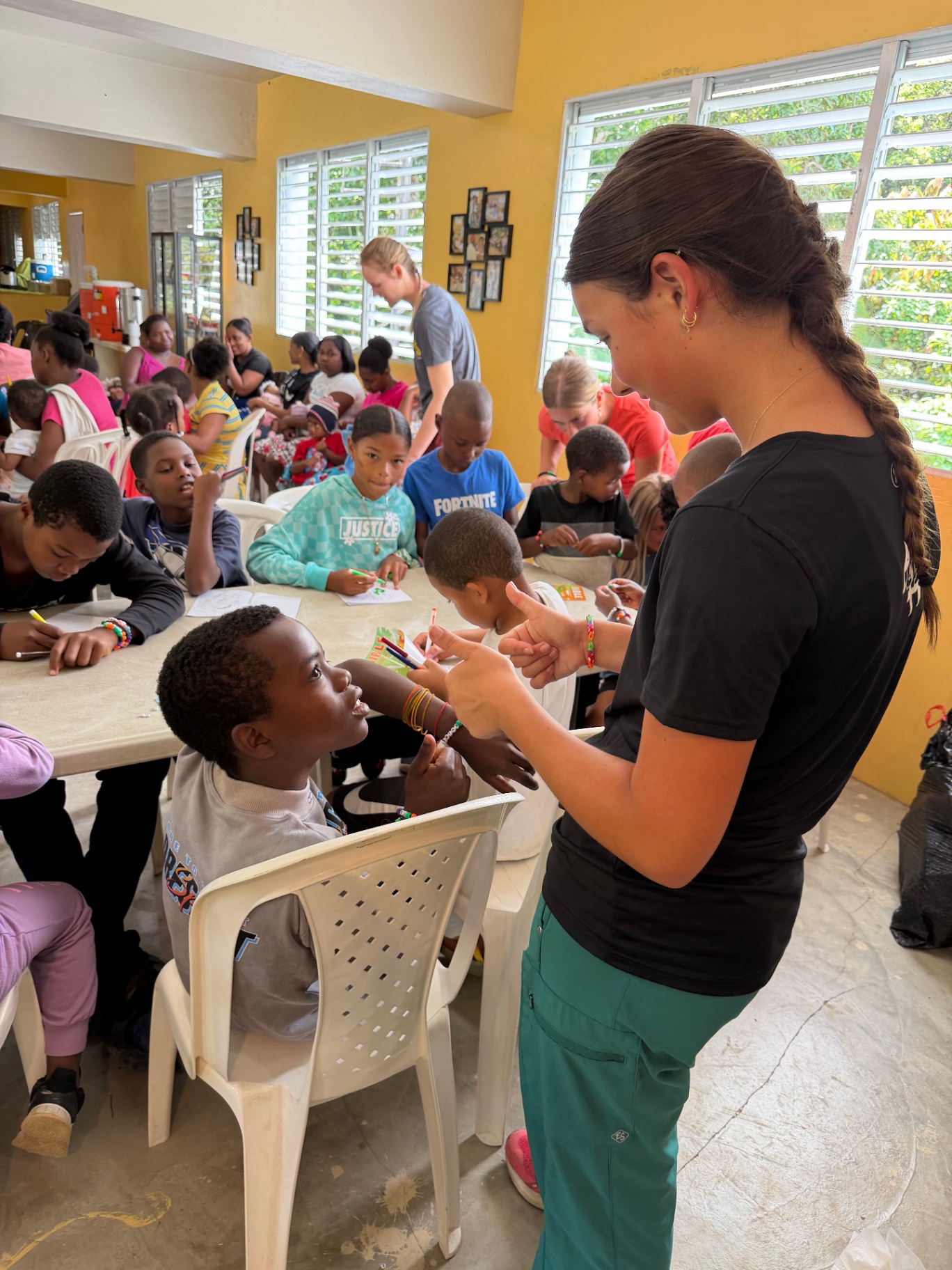 Volunteer in scrubs handing out markers to children at kids ministry