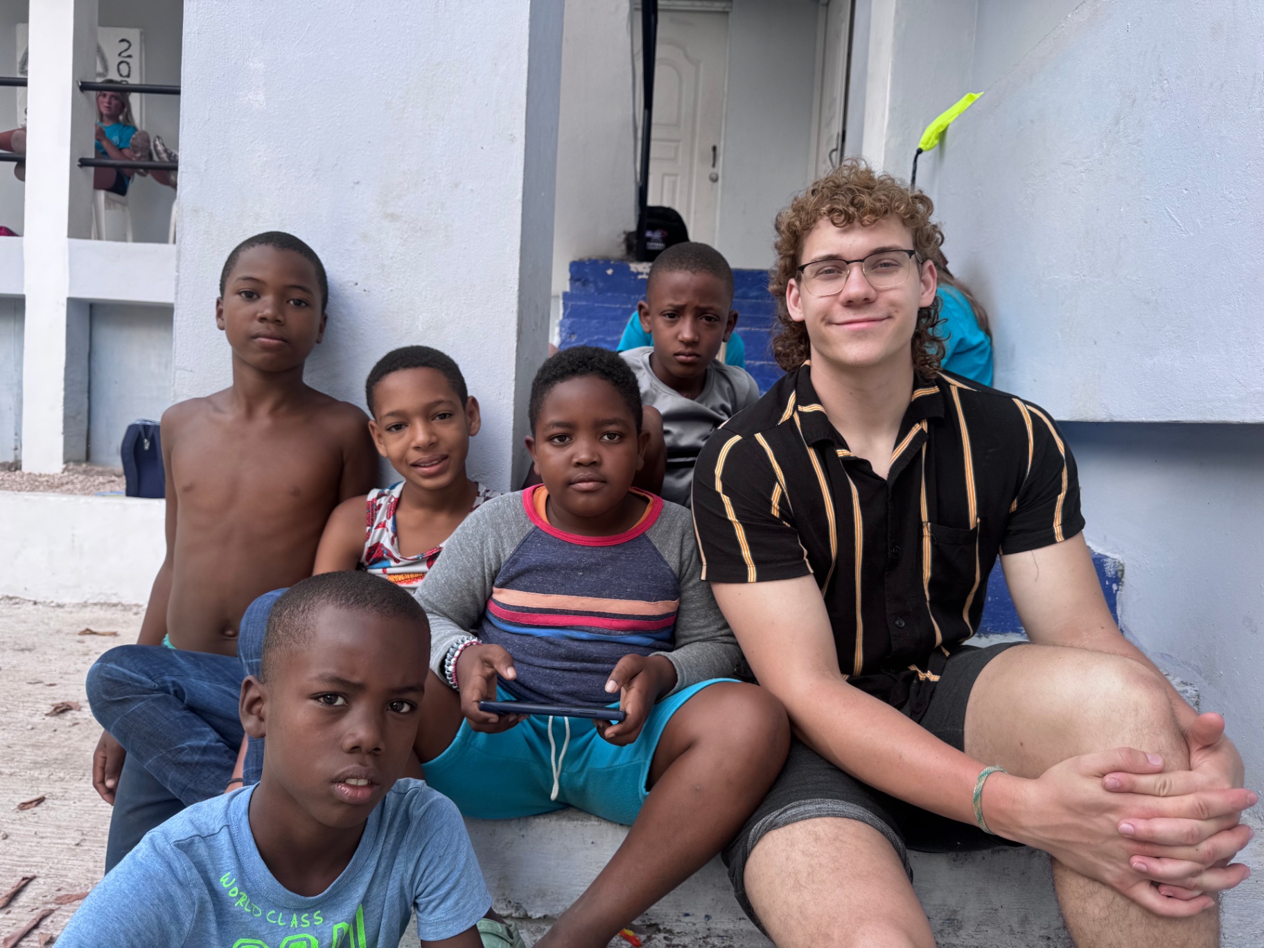 Young volunteer sitting with local boys outside a building