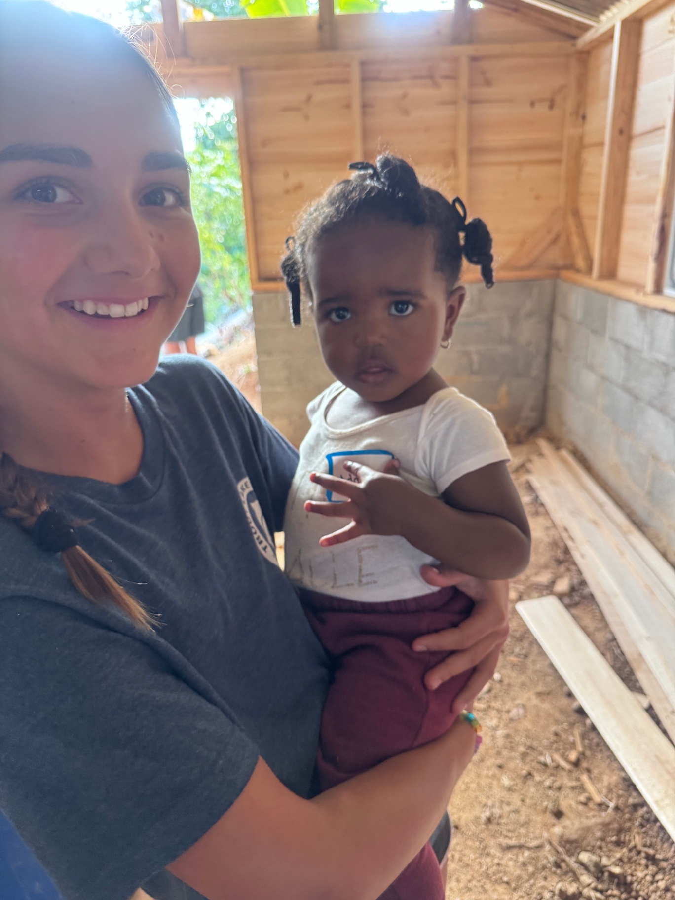 Volunteer holding a young child inside a home under construction