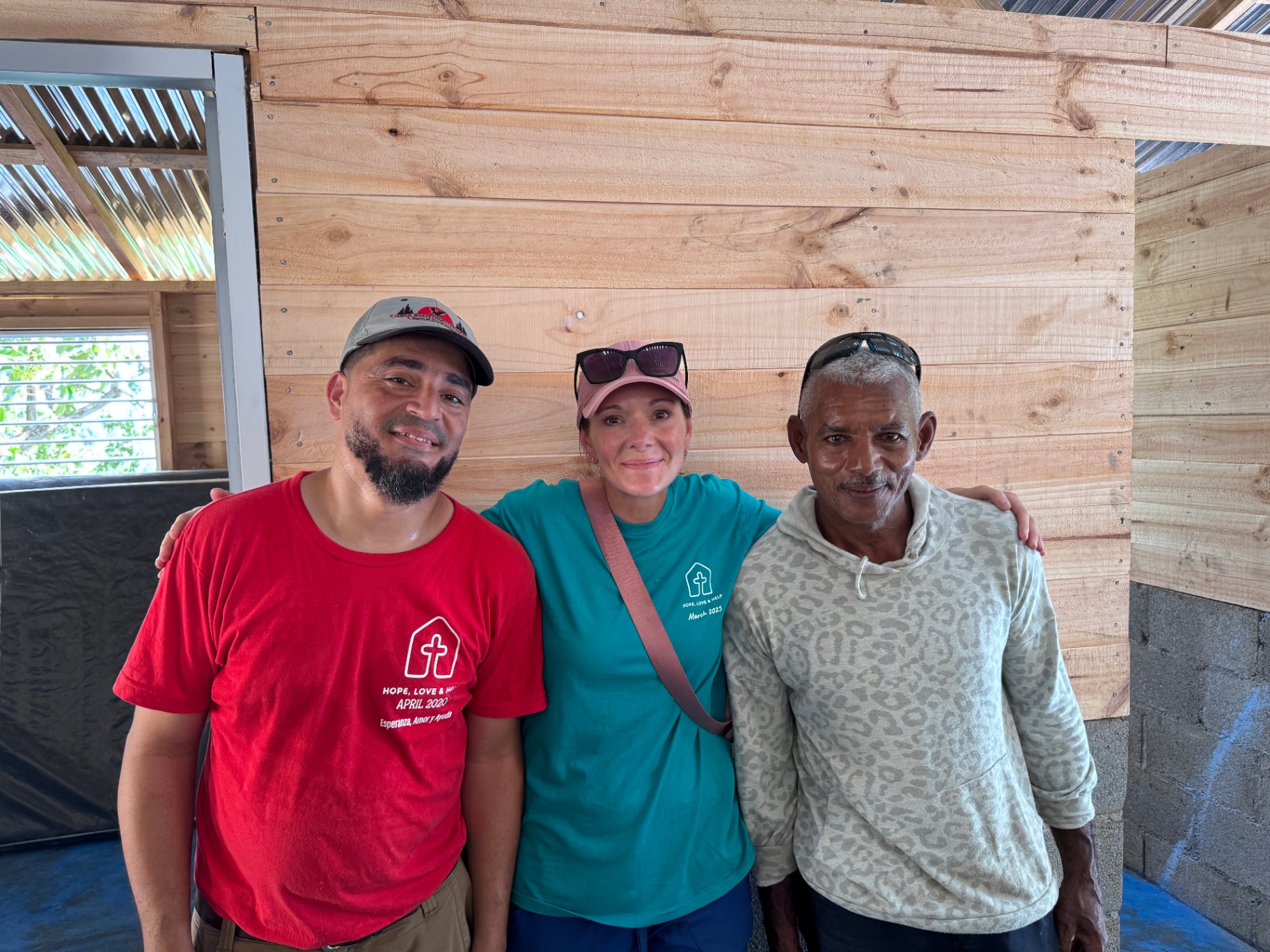 Volunteer posing with two local men inside a newly built home