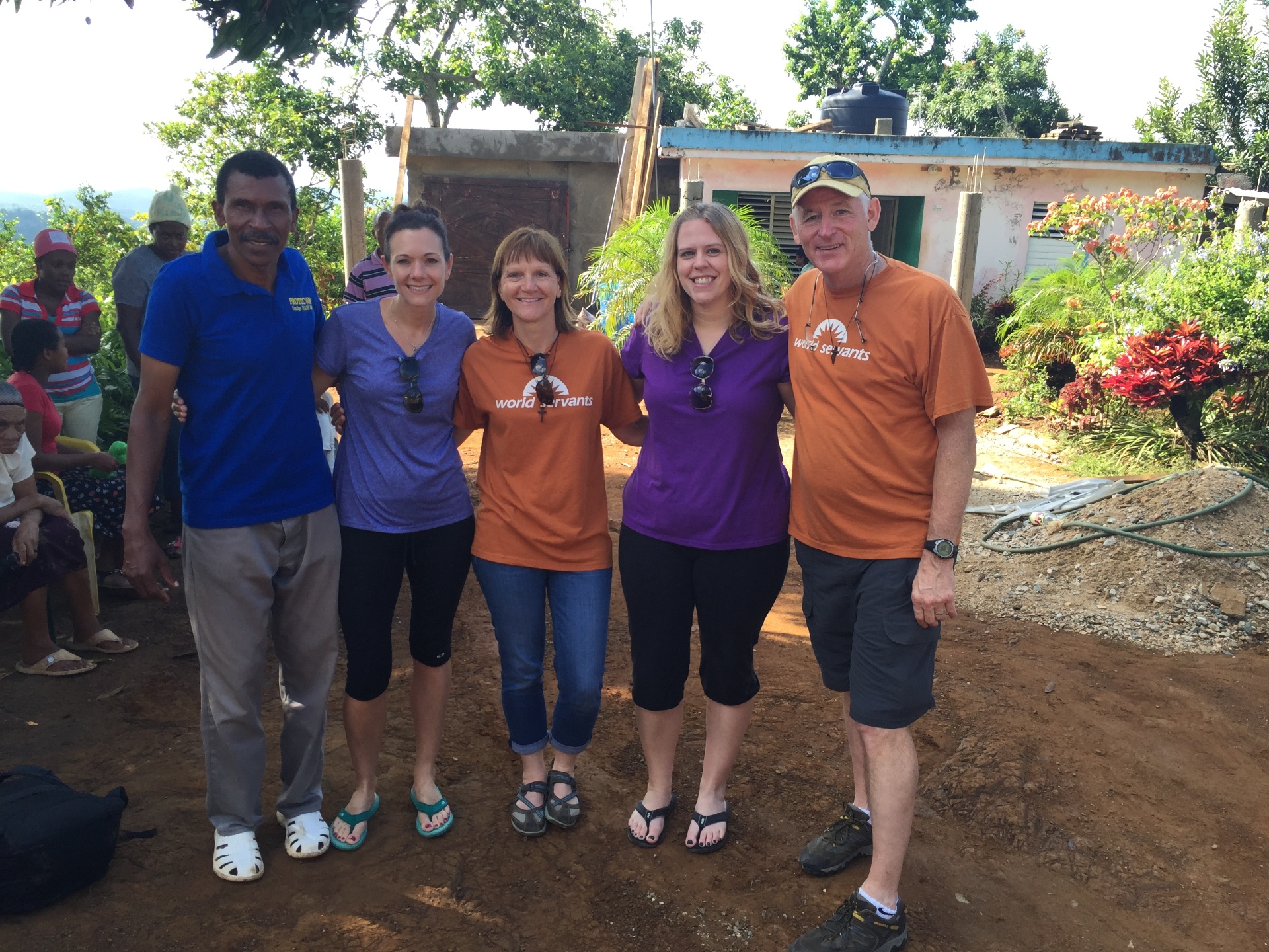 Group of volunteers and a local man posing together in front of a home