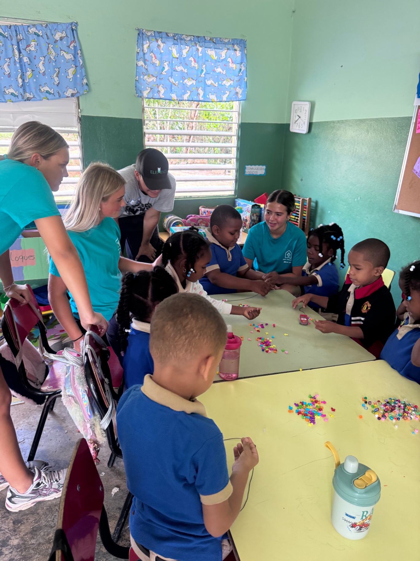 Volunteers helping children with crafts in a classroom