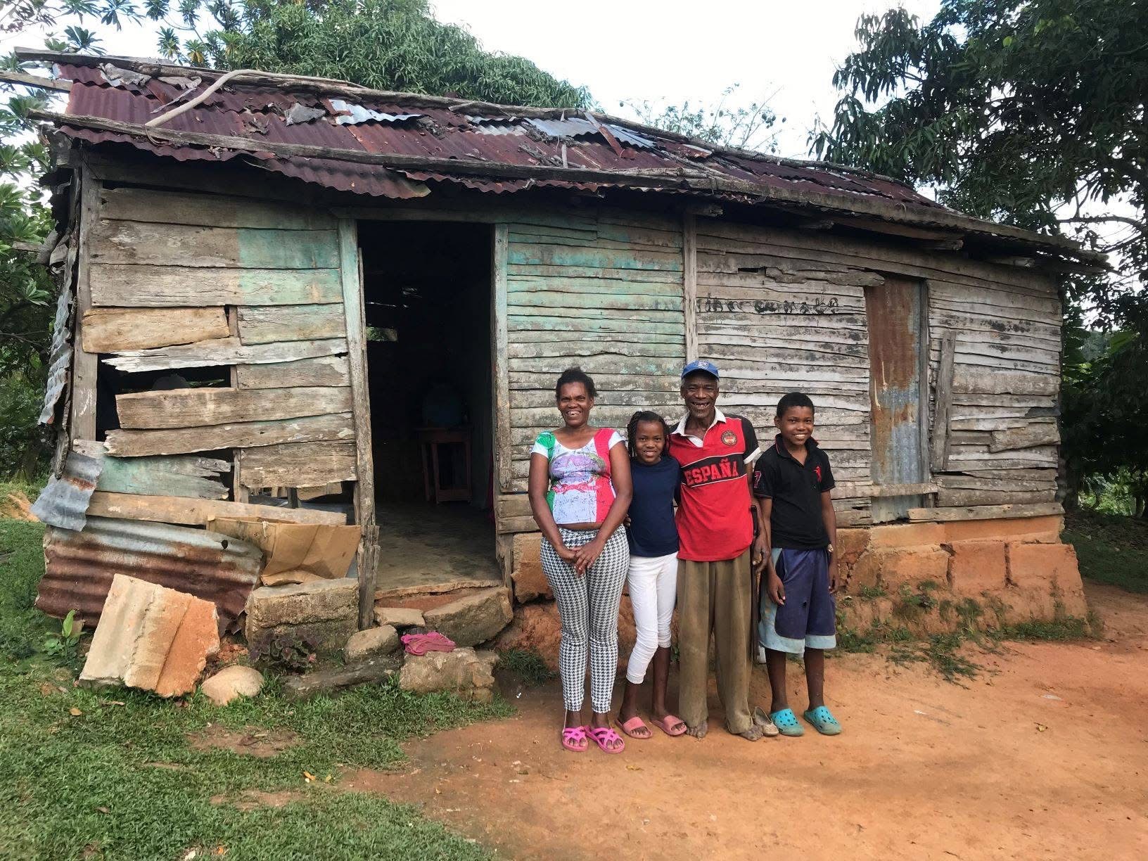 Local family standing in front of their wooden home