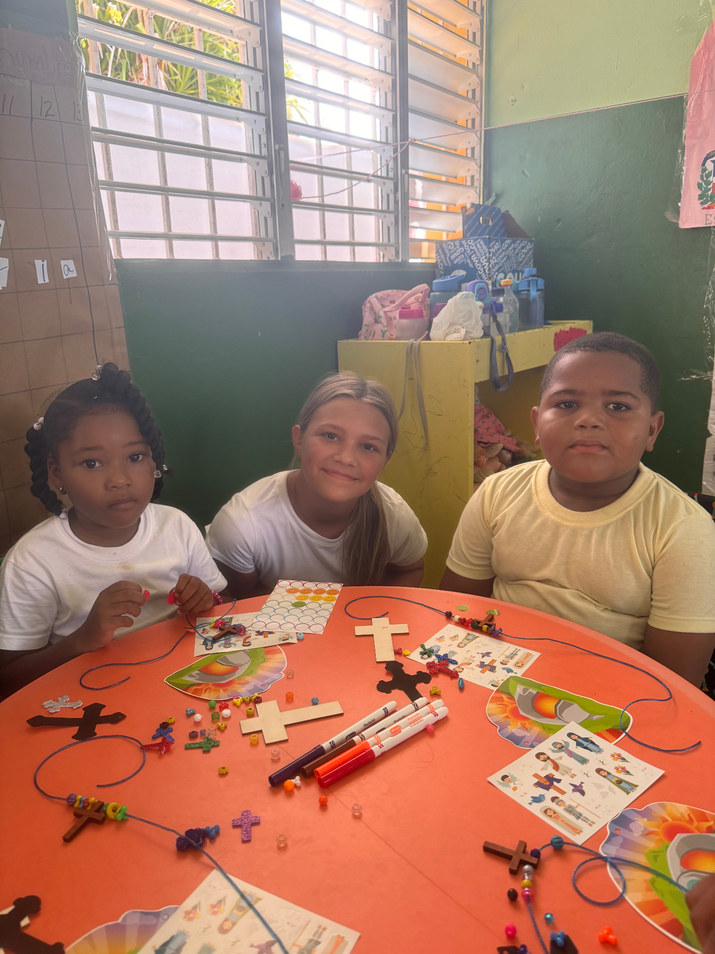 A volunteer doing craft projects with two children at a school table
