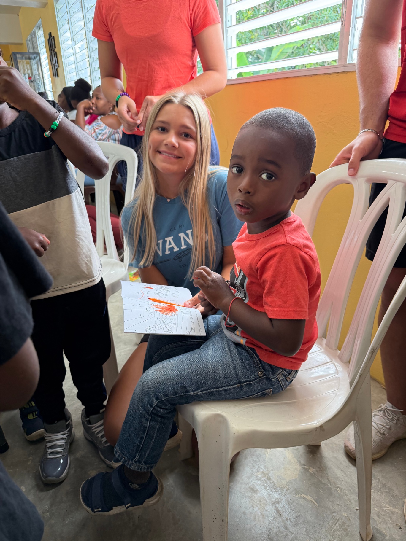 Volunteer smiling with a young child coloring together